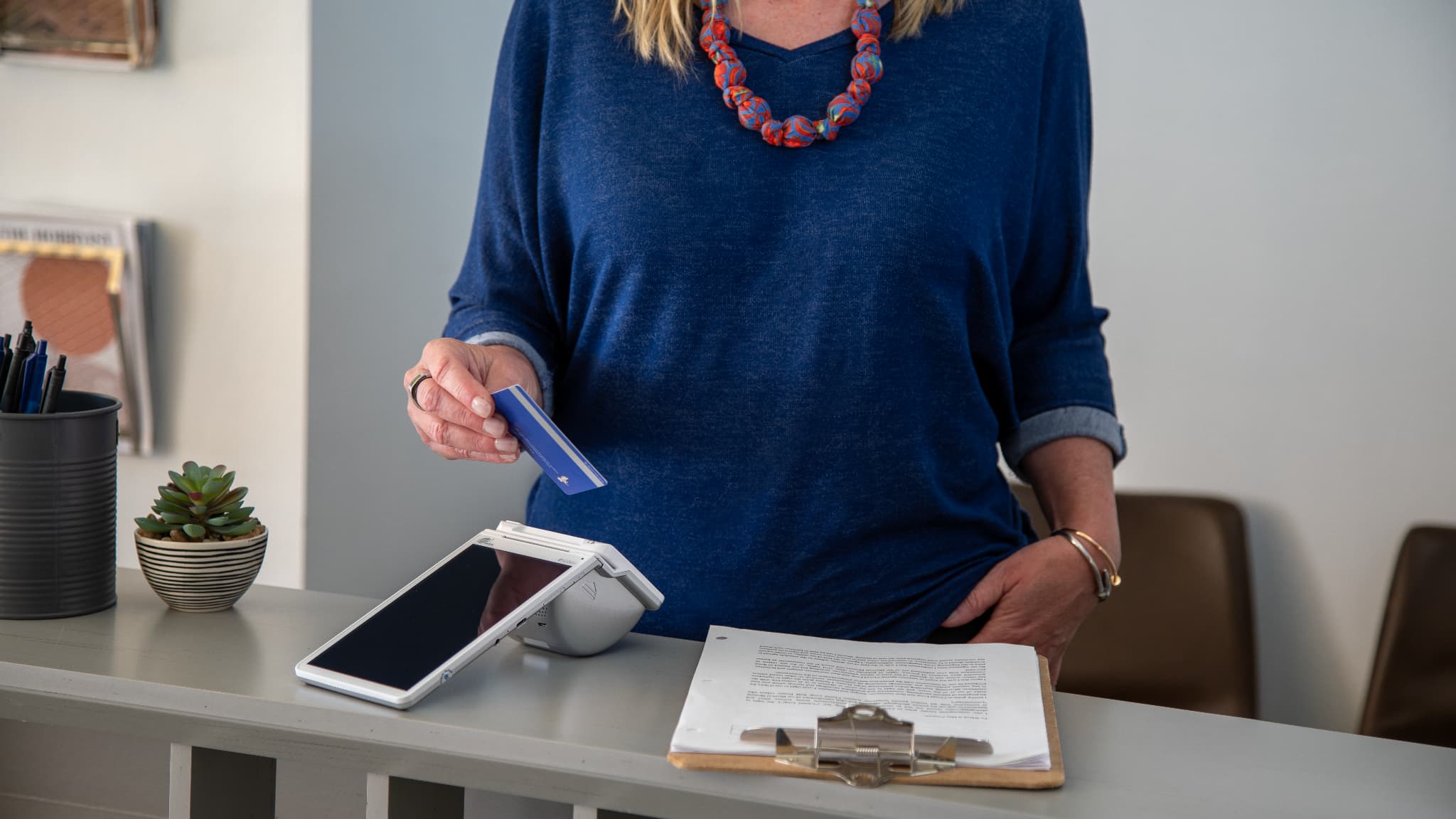 Woman using pos credit card reader in doctors office